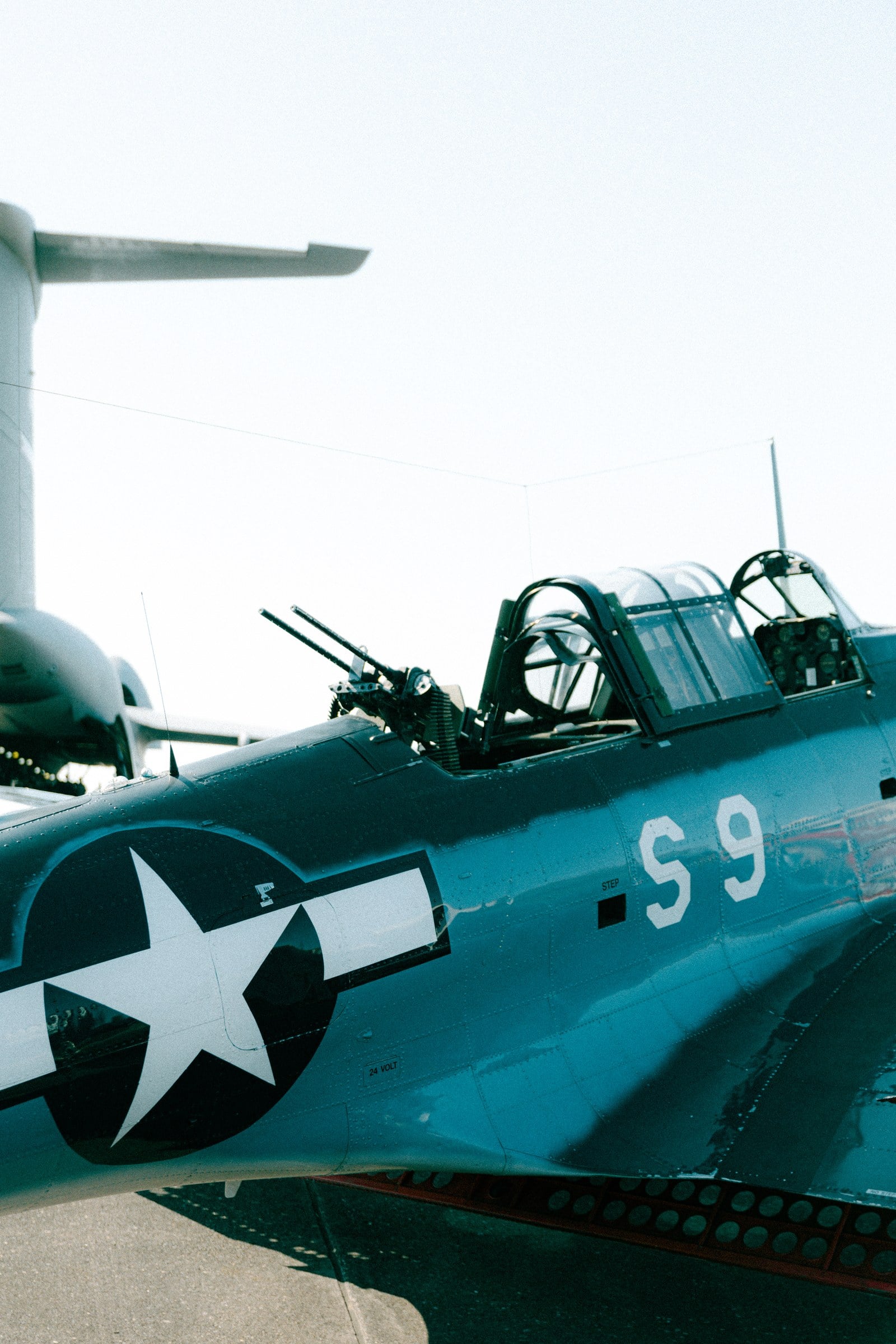 The cockpit and fuselage of a teal aircraft marked S9.