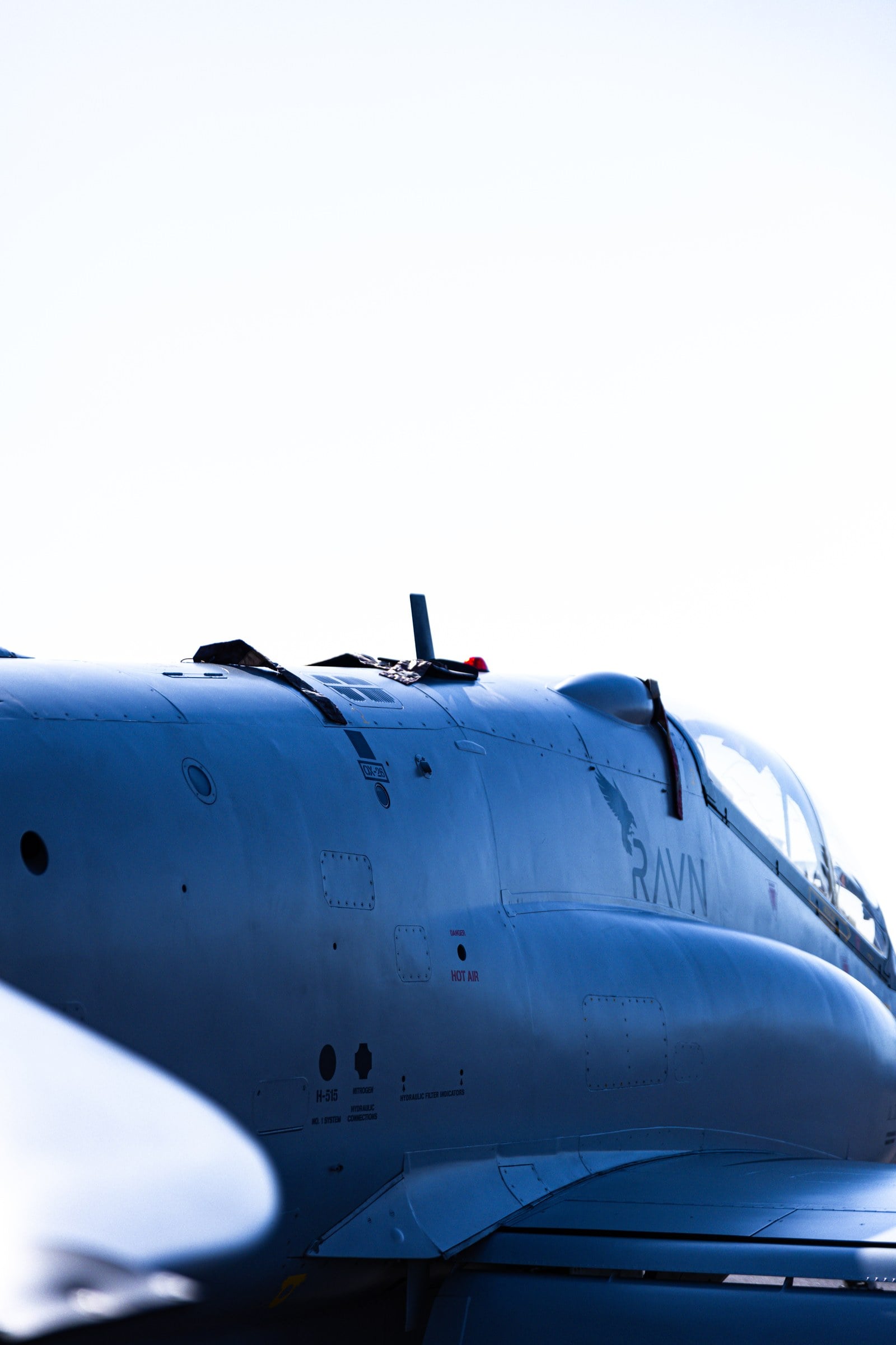 A blue aircraft fuselage photographed against a bright sky.