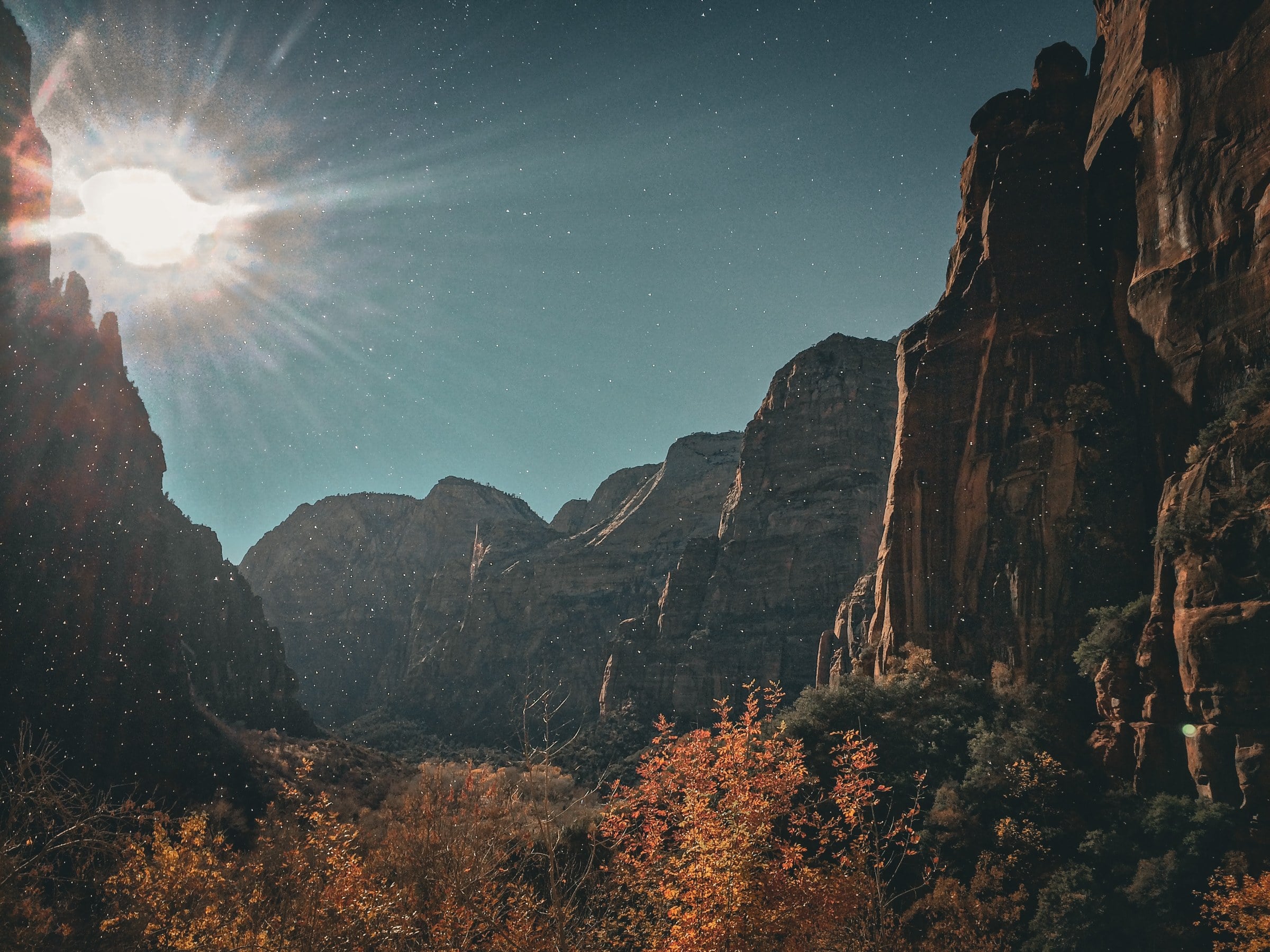 Sunlight breaking over canyon walls and autumn trees.
