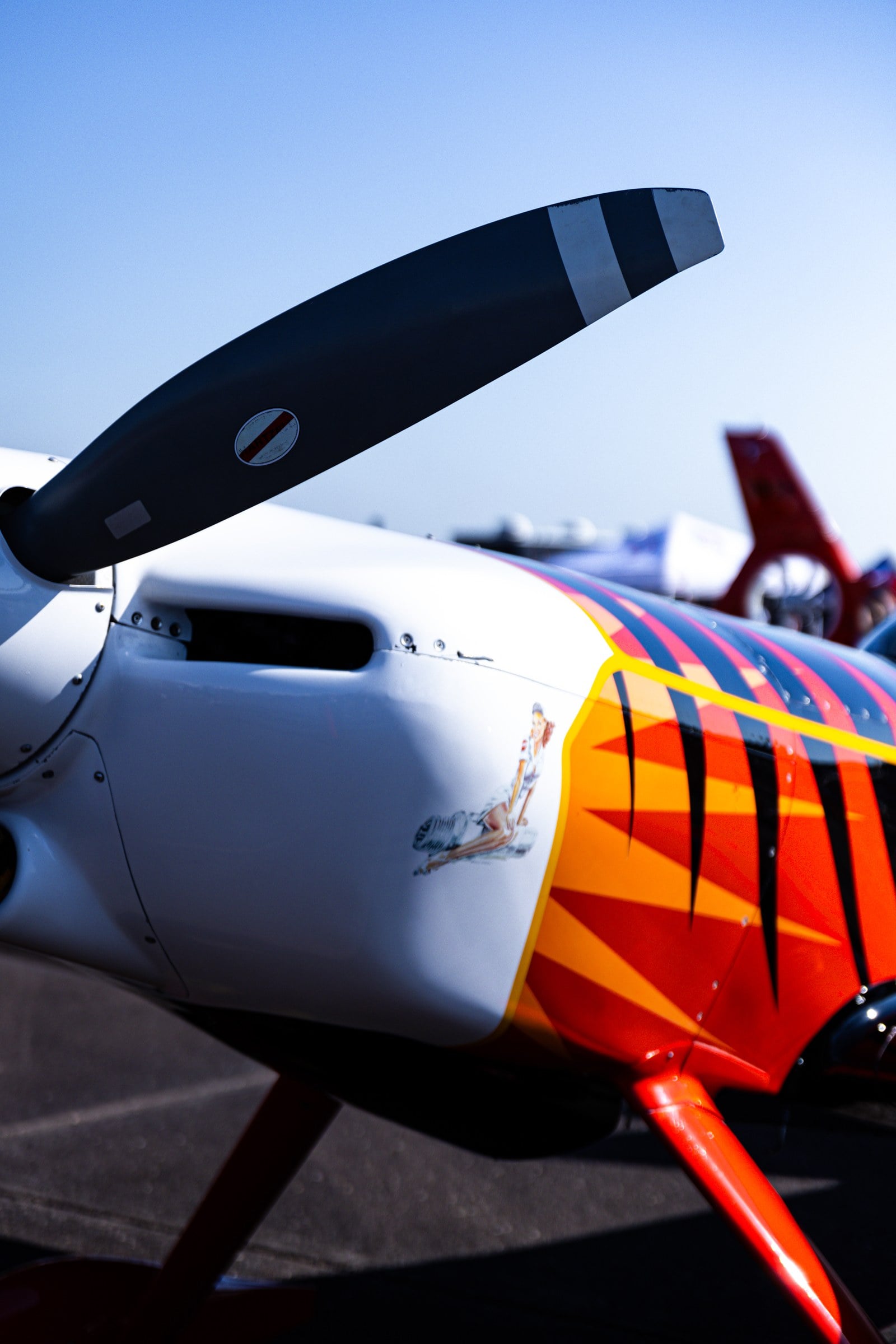 A close view of a propeller and a brightly painted aircraft nose against a blue sky.