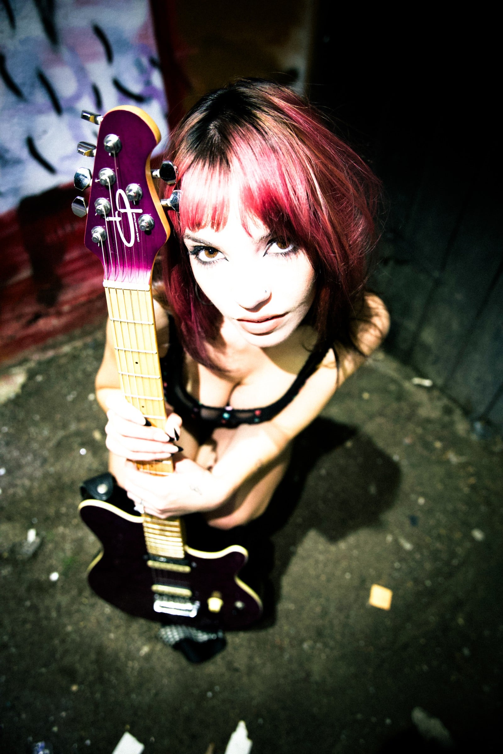 An overhead portrait of a musician holding a purple electric guitar.
