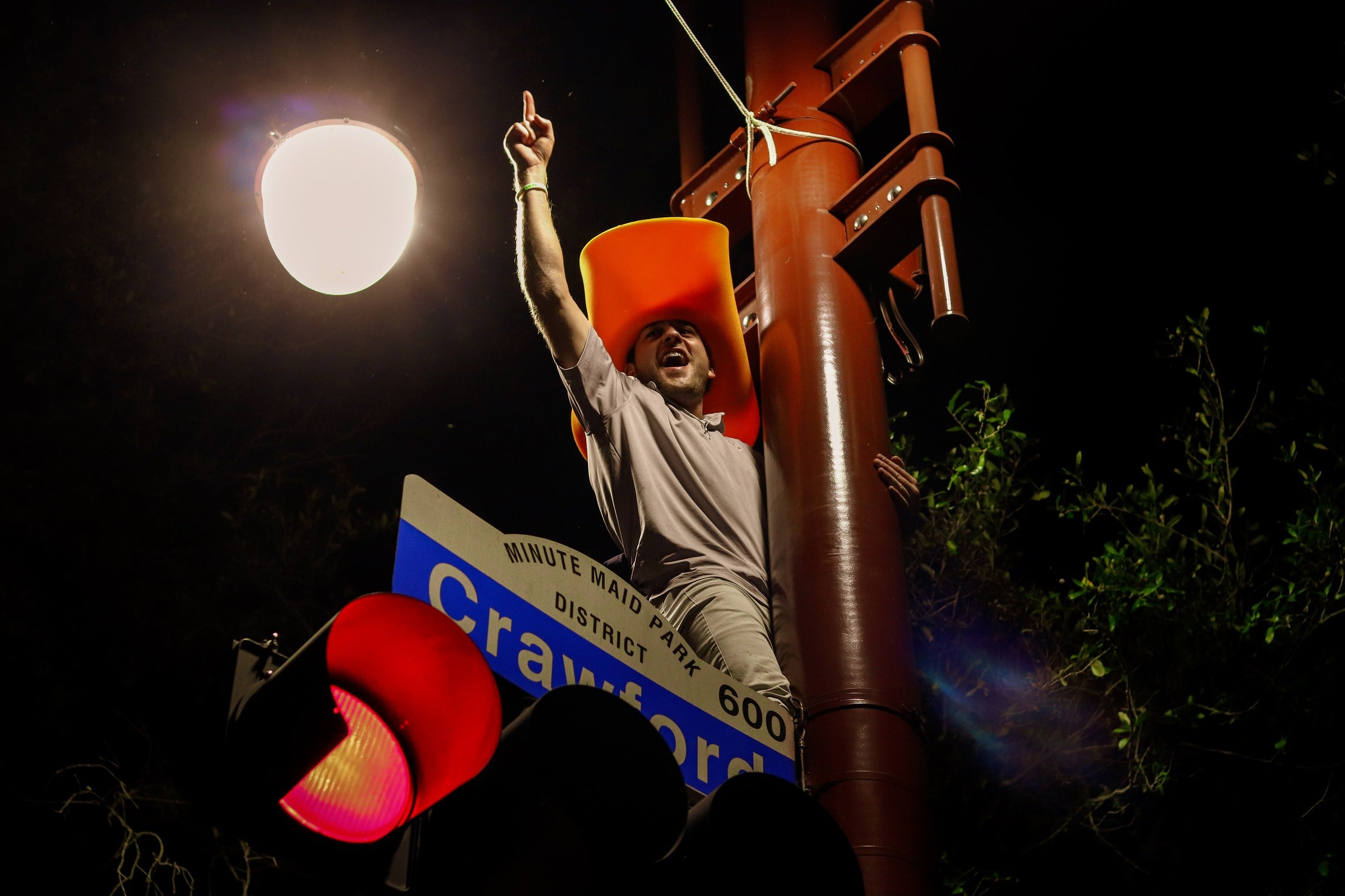 A large illuminated figure beside a roadside sign at night.