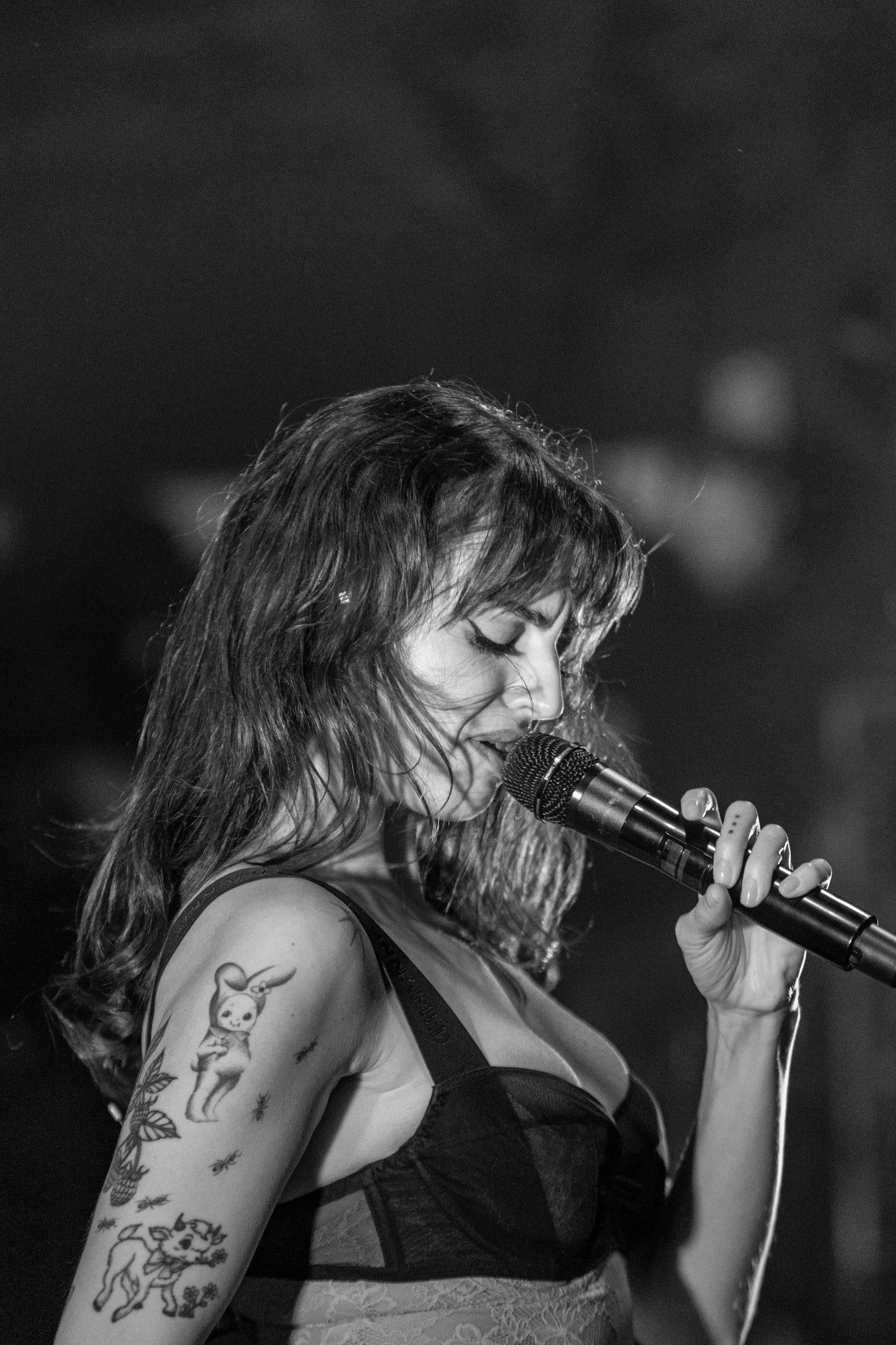 A close black-and-white portrait of a vocalist singing into a microphone.